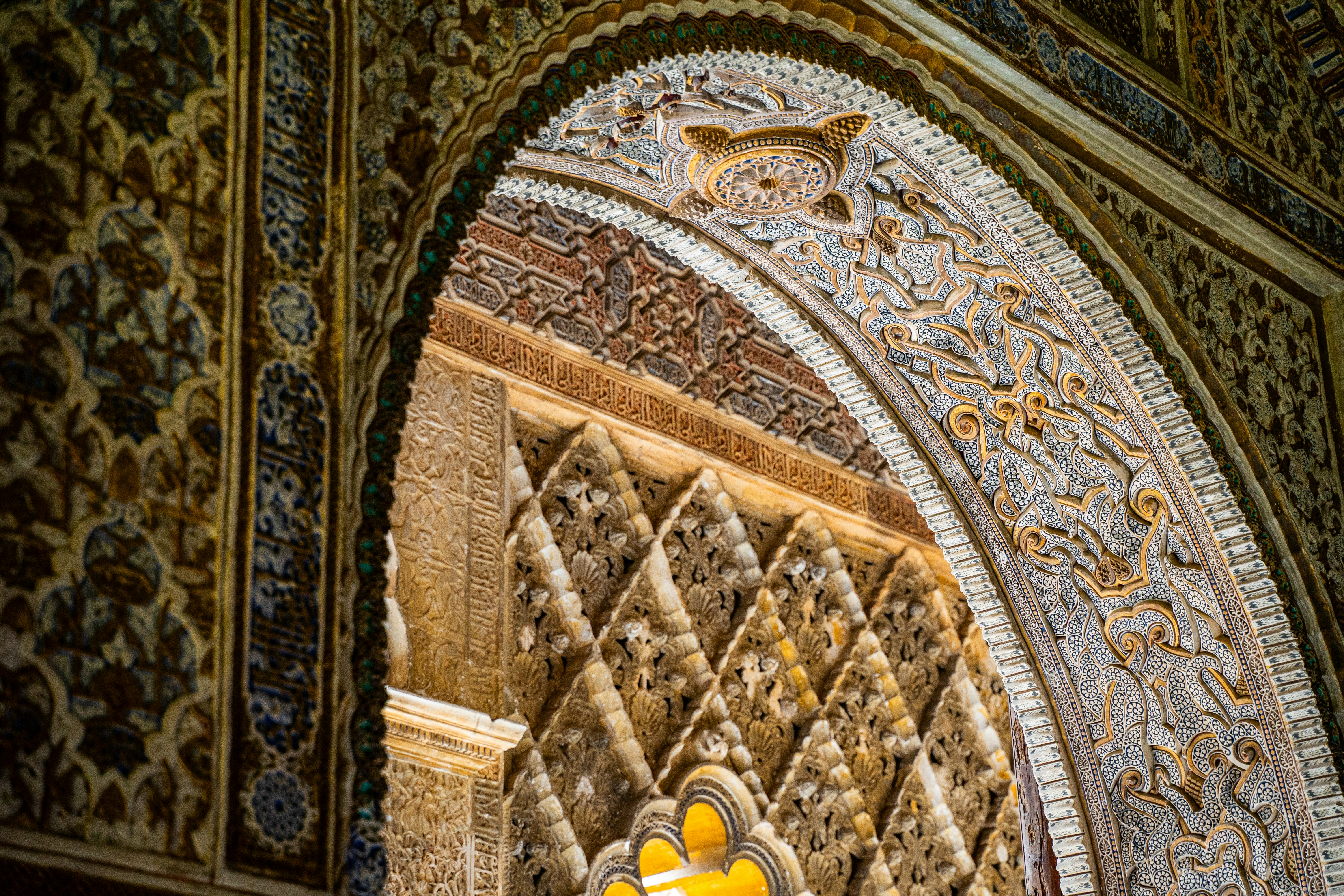 a yellow traffic light in front of a decorative wall