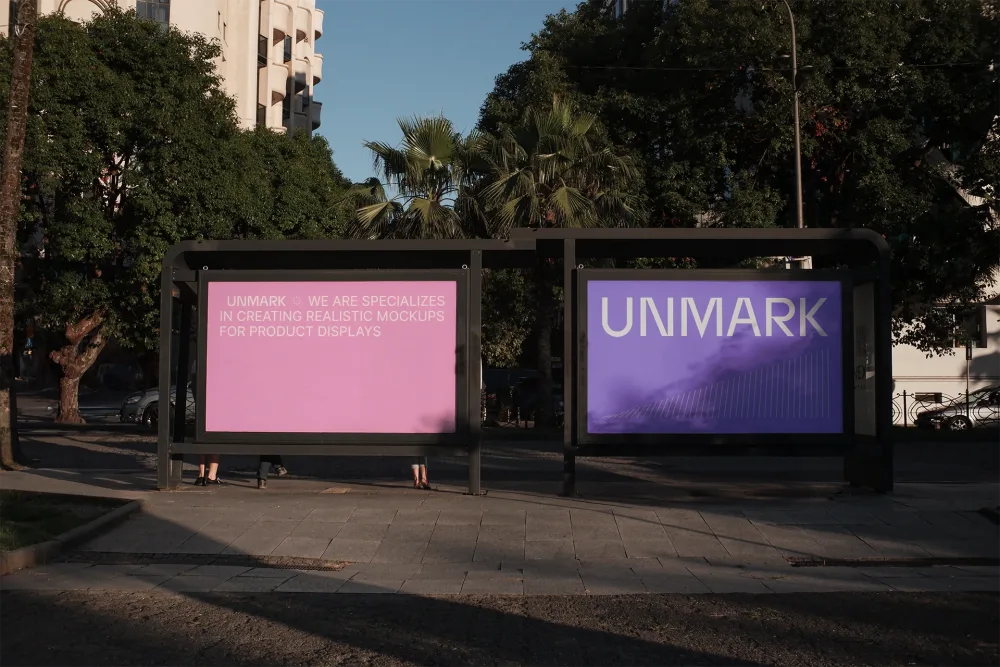 Two large outdoor advertising boards at a bus stop, featuring vibrant pink and purple designs with bold typography, set against a city backdrop with trees and sunlight.