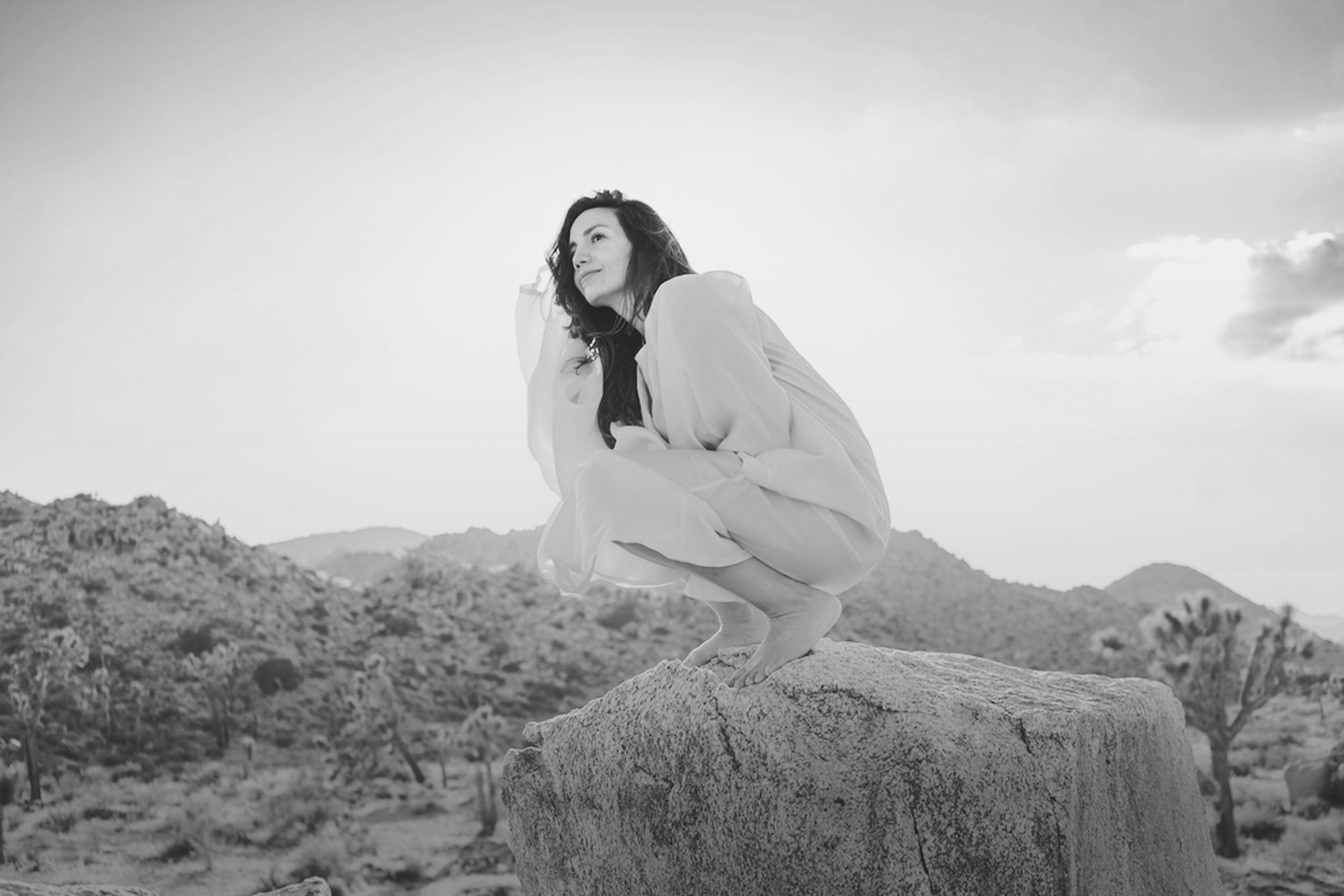 Dr. Joyce Braverman crouching on a boulder in the desert