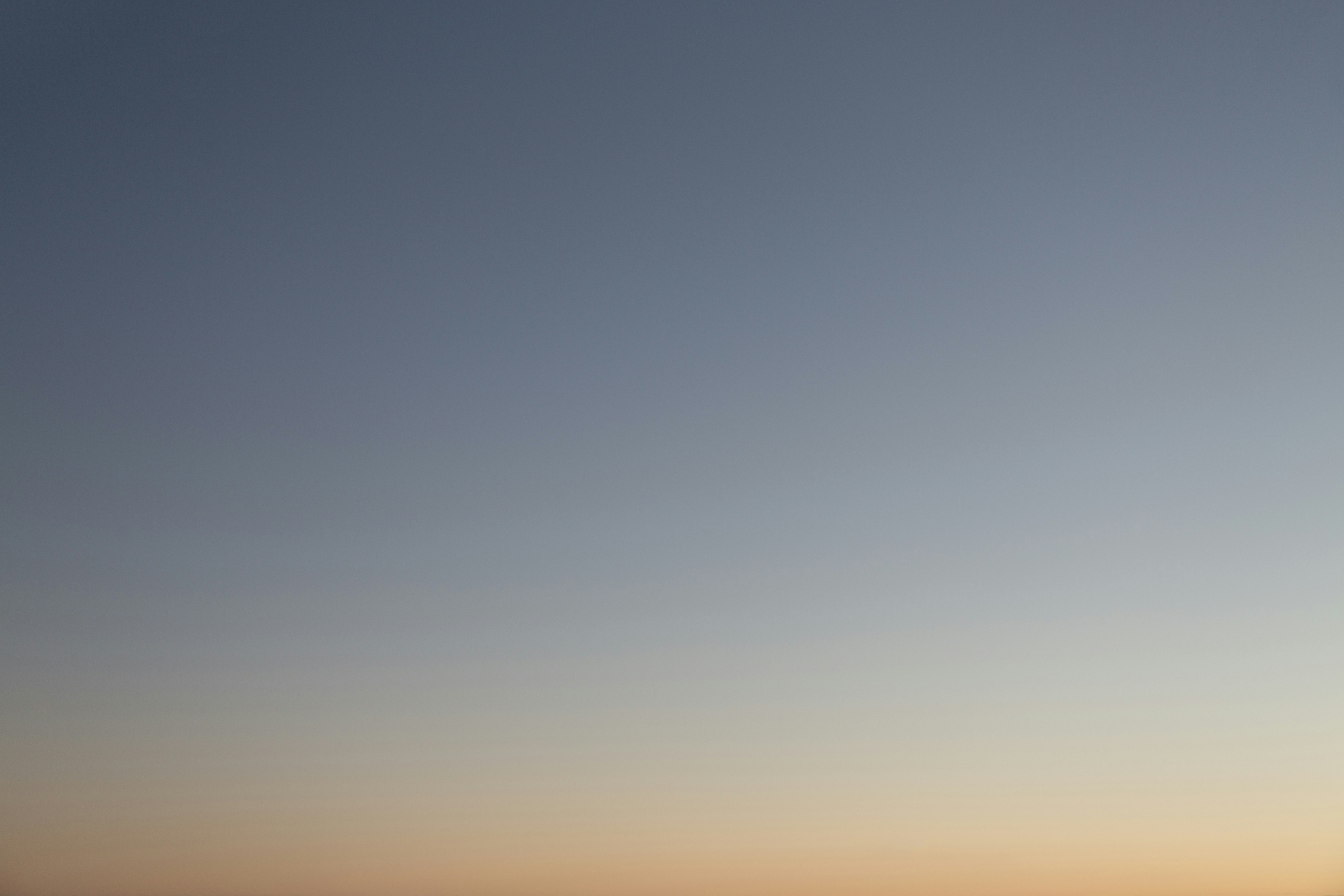 a plane flying in the sky at sunset