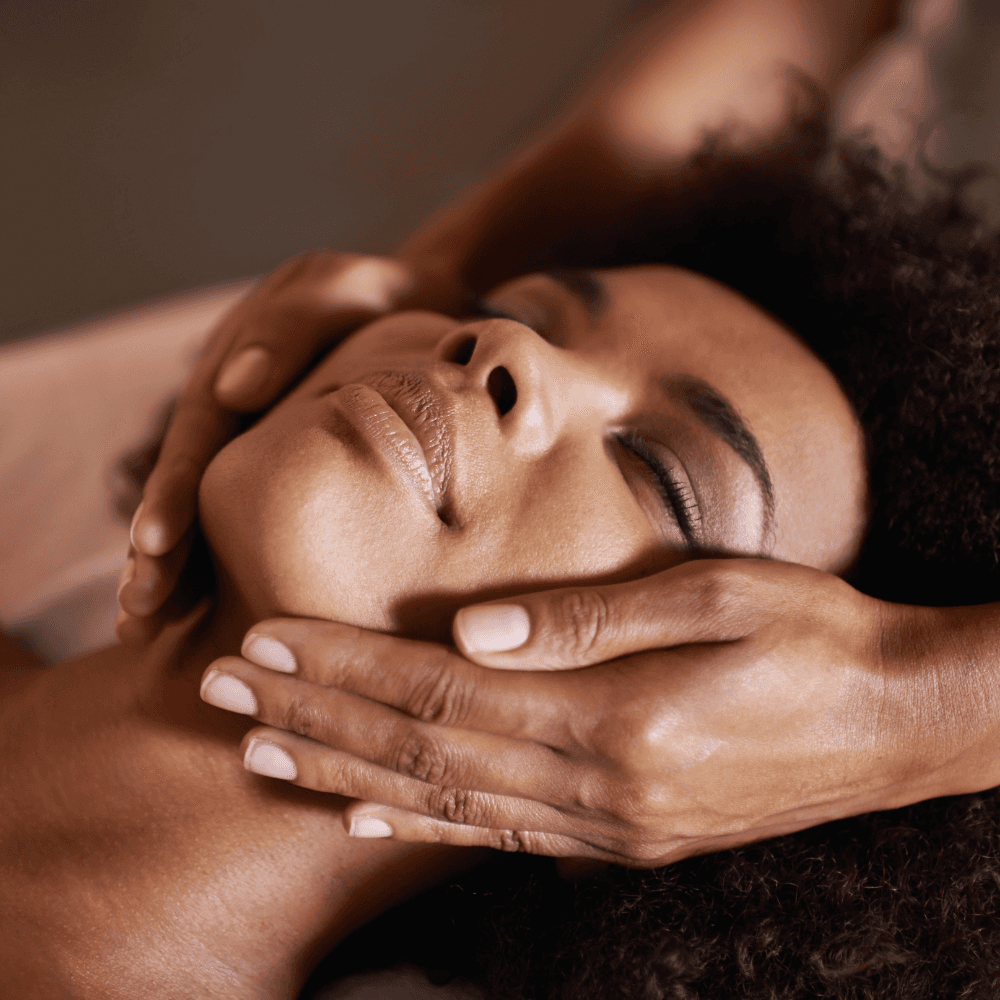Woman relaxing on a massage table with candles in the background, receiving a back massage in a spa setting