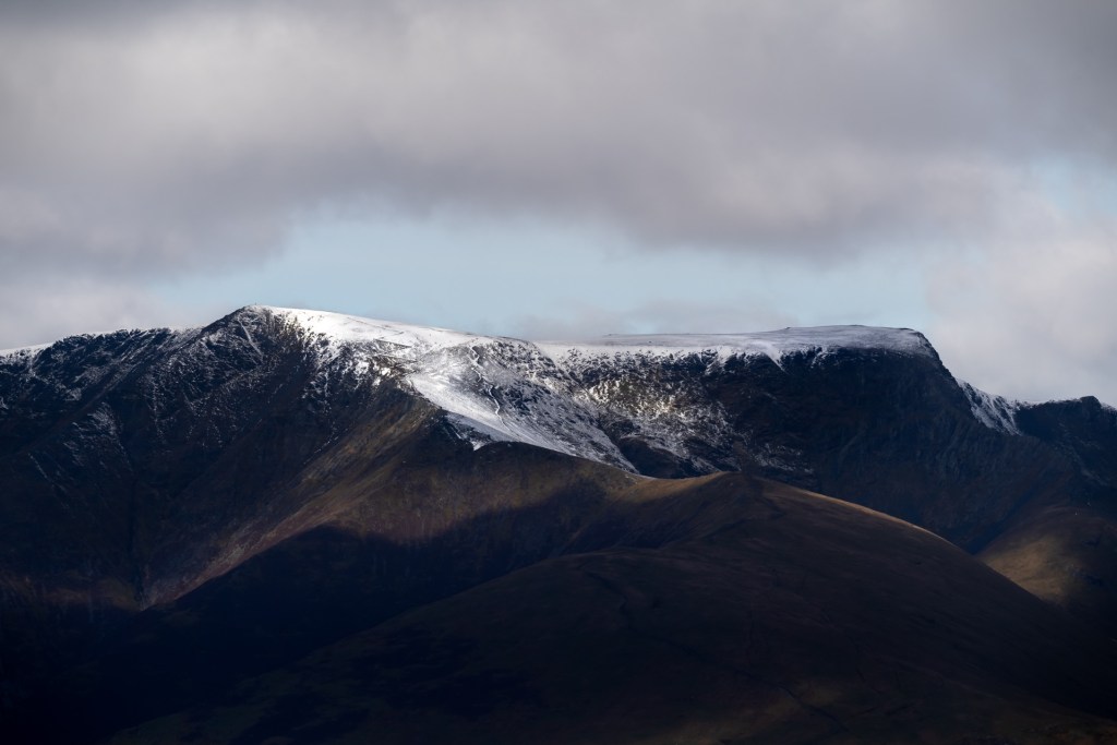 The mighty Blencathra in a dark moody scene with snow on top. You can even make out a zig-zag path up the side.