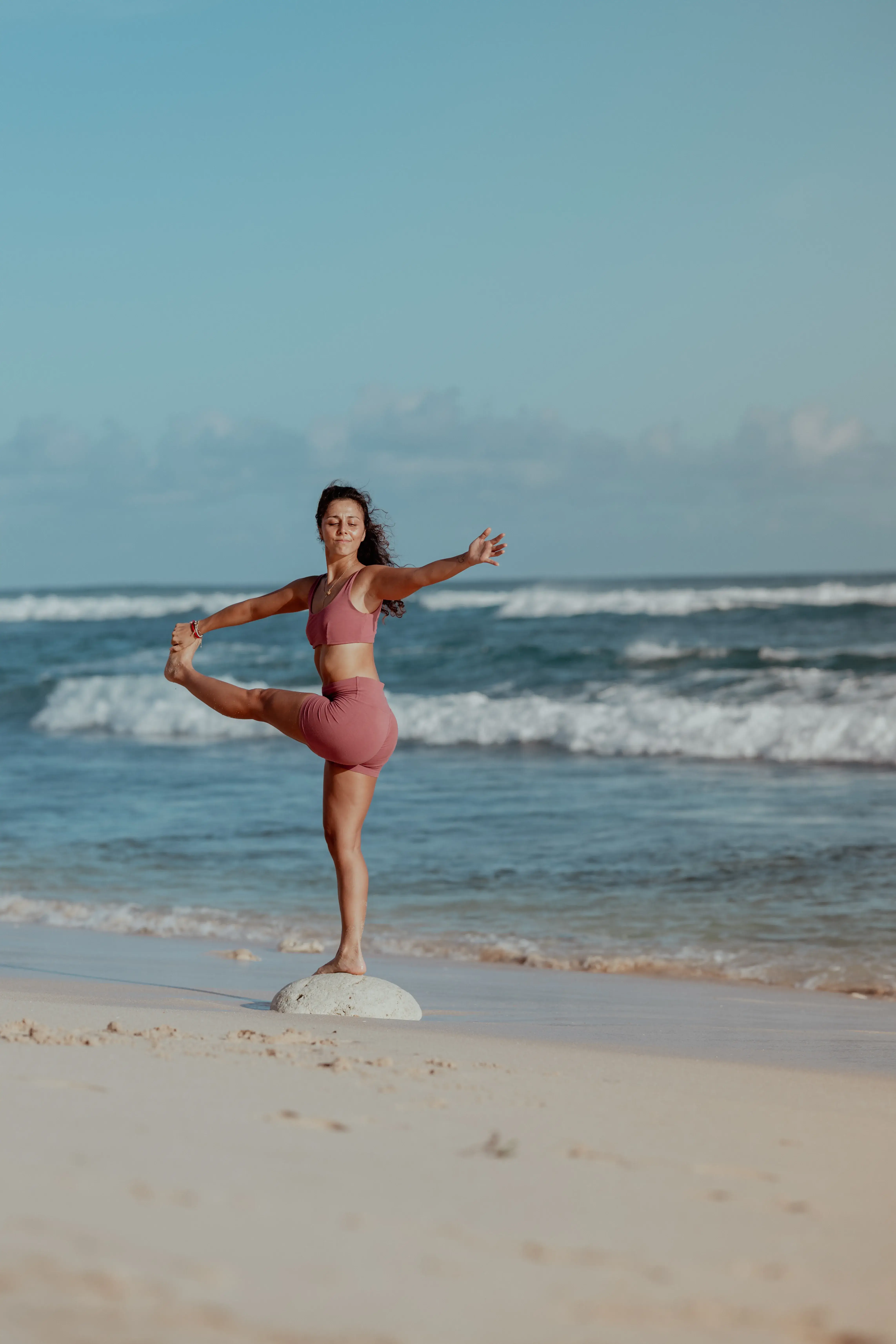 Woman practicing standing balance pose on the beach during the 200-hour yoga certification program in Bali