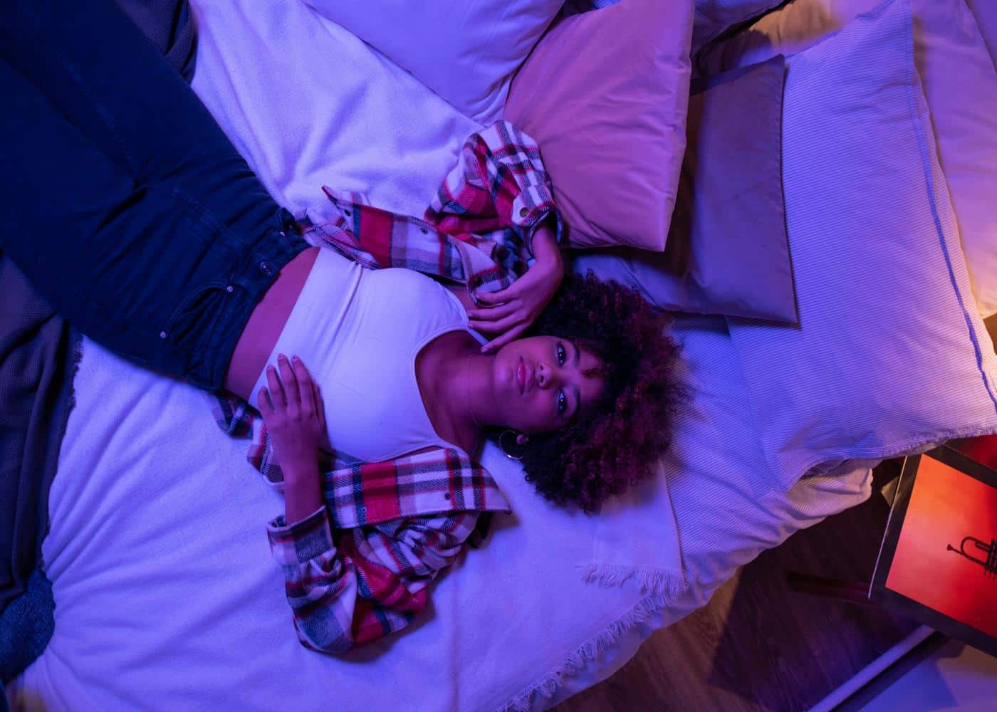 Night owl lying in a messy bed and looking at the camera