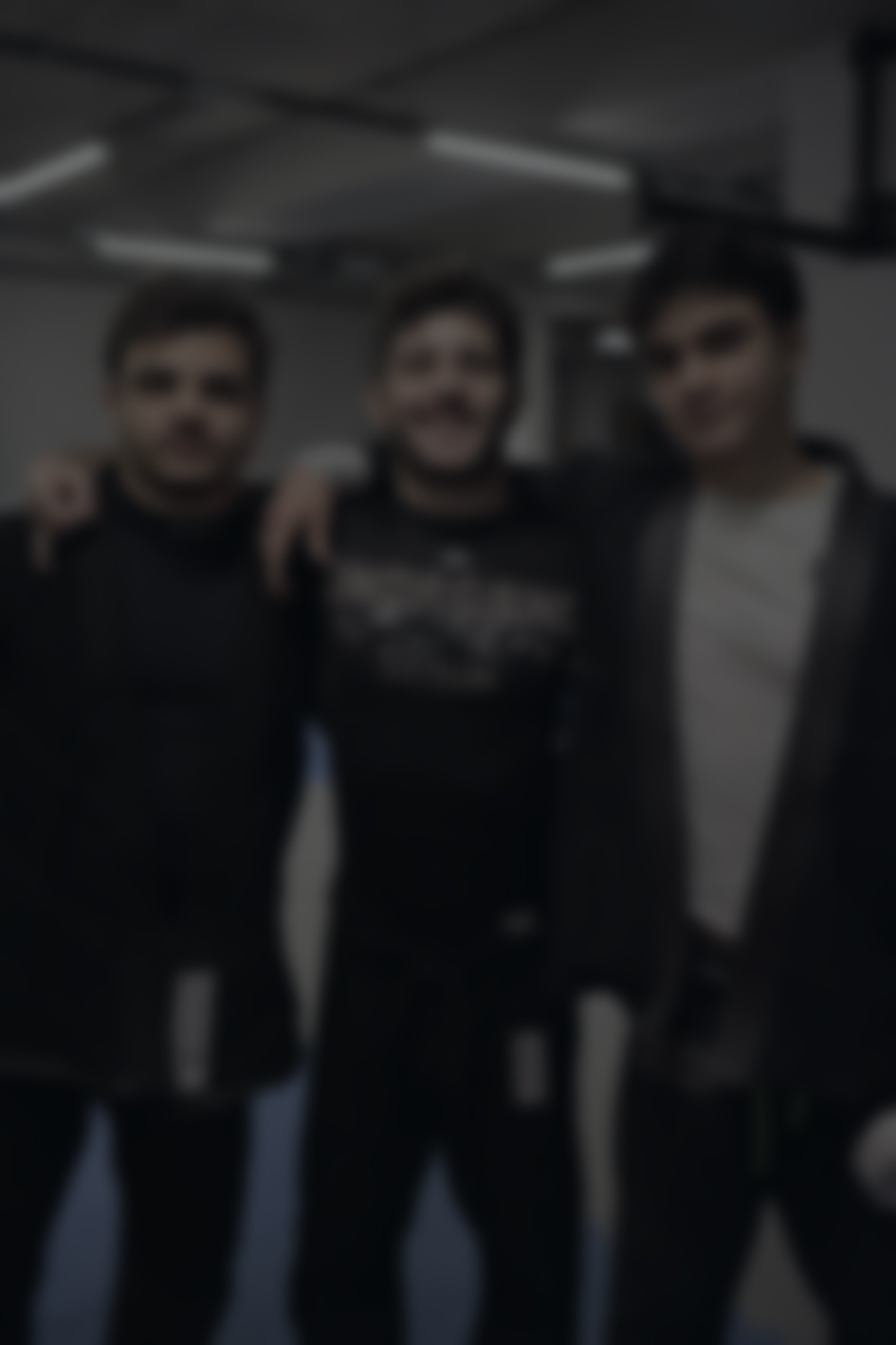 a blurred image of coach Erkin with two students at a belt ceremony