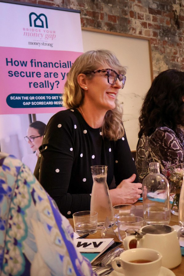 woman sits at table and smiles