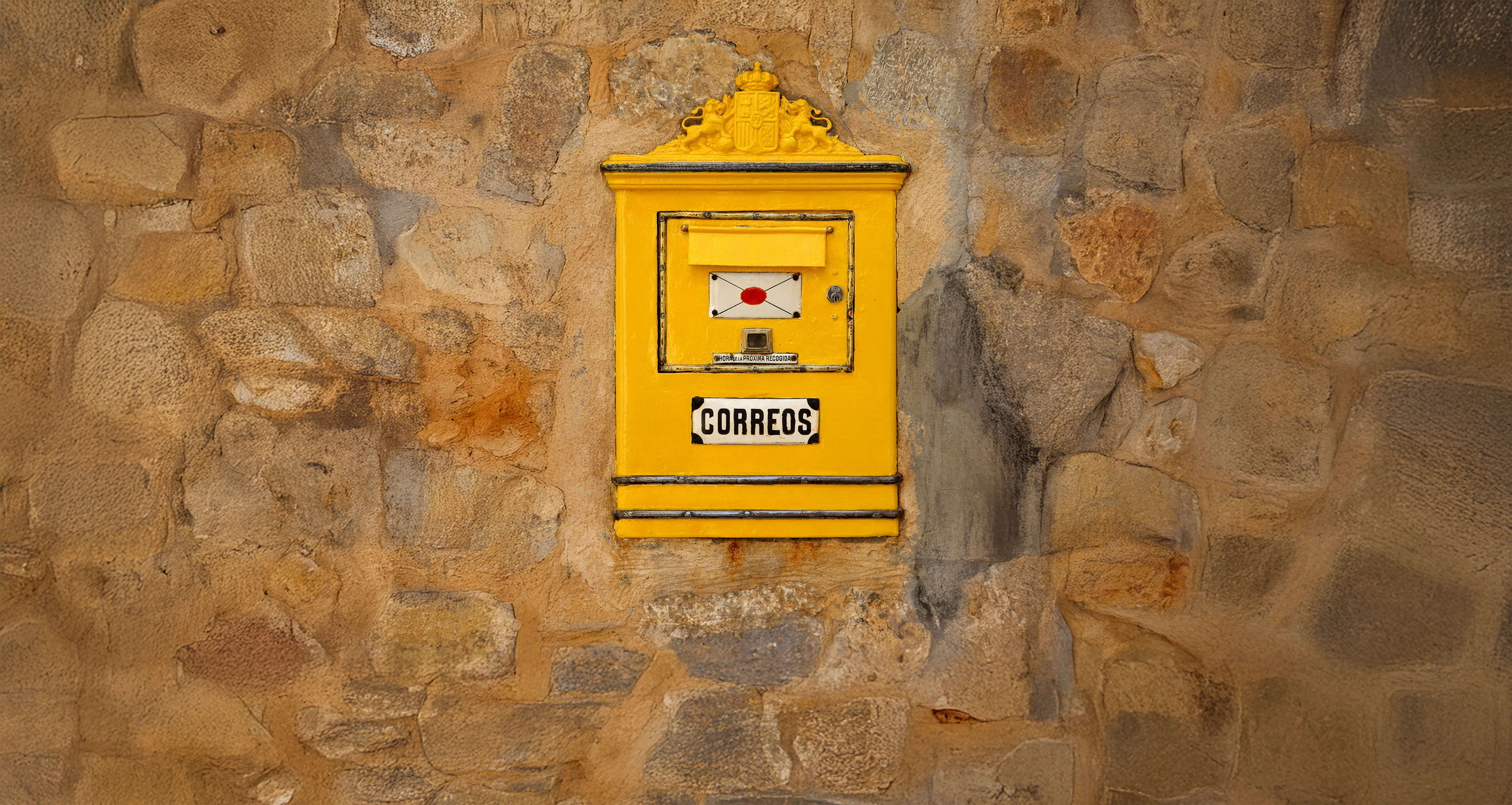 Bright yellow vintage mailbox on stone wall — metaphor for client feedback and testimonials in the GUFR experience section.
