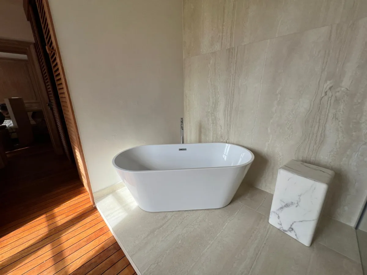 Baignoire autoportante ovale blanche sol carrelage beige marbre salle de bain moderne