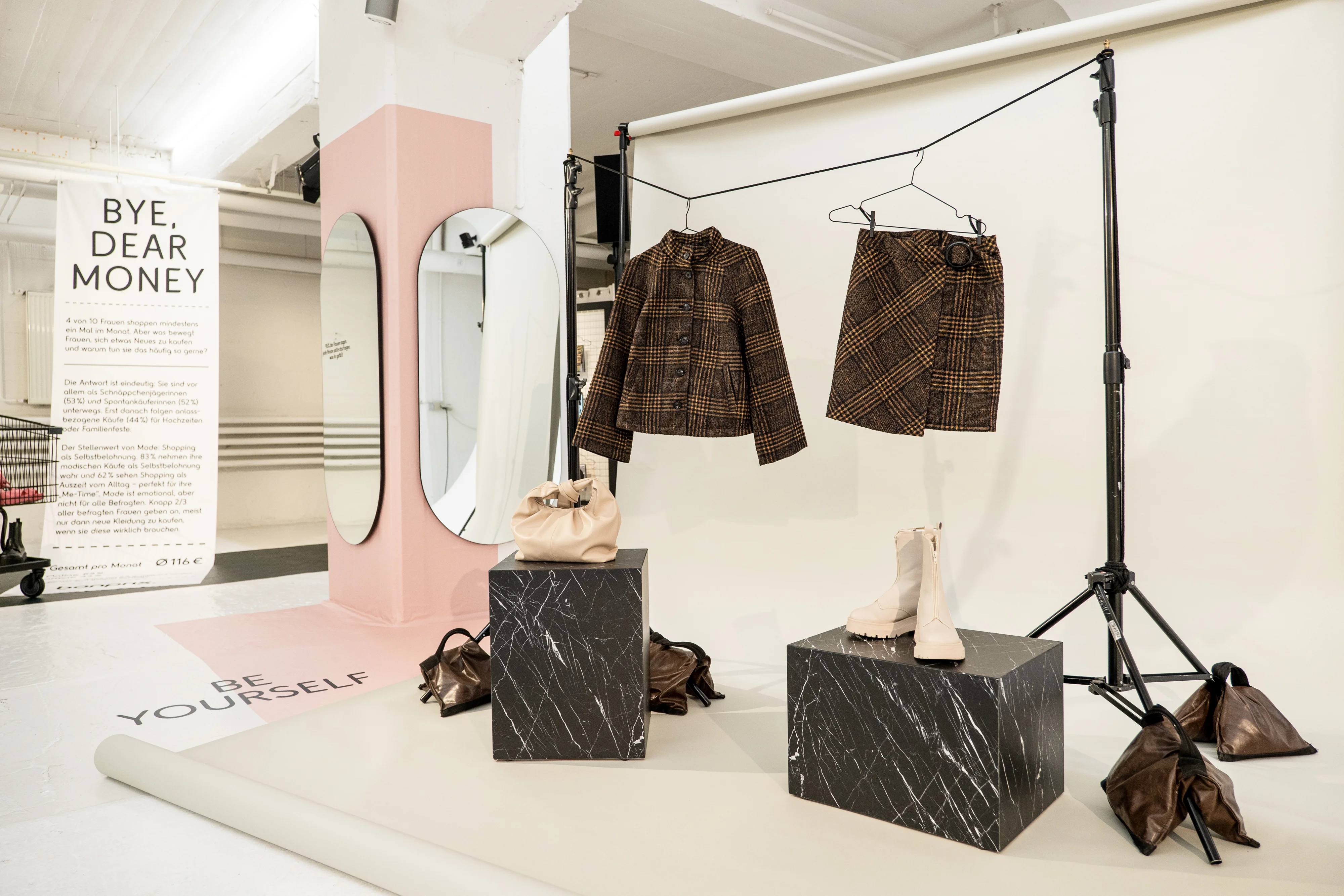 Photo set with tweed outfits on hangers, marble cubes, boots and leather bags at the Bonprix exhibition.