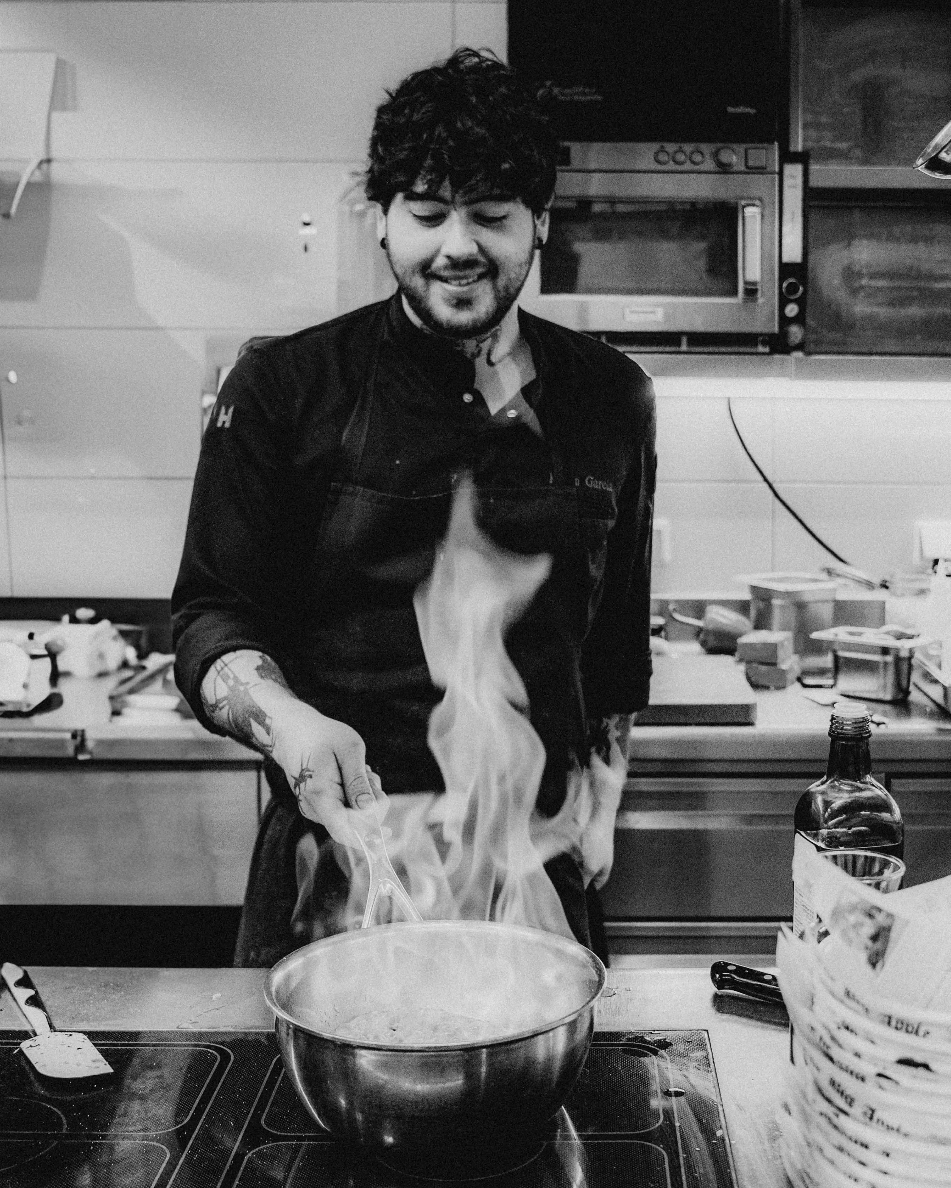 A person in a kitchen cooks, holding a steaming pot filled with food, surrounded by utensils and ingredients.