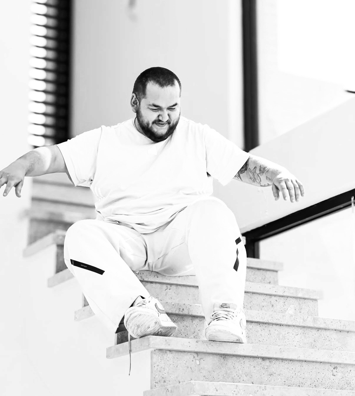 A thoughtful young person with dark hair gazes to the side, captured in soft black and white lighting.