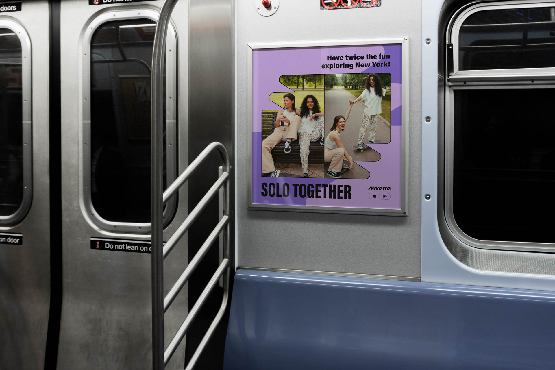A silver subway train car with a purple advertisement for the movie "Solo Together" mounted on its side. The ad features four people sitting together on a bench and includes the tagline "Have twice the fun exploring New York!" and the Warner Bros. logo. The train car has multiple windows and a metal handrail is visible beside the advertisement.