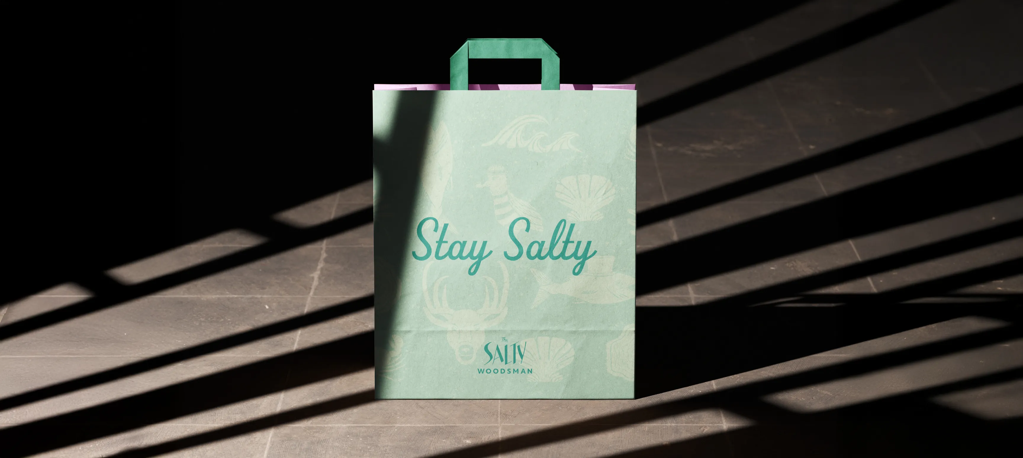 A Salty Woodsman gift bag with a light turquoise collage illustration and writing in teal script that says "Stay Salty."