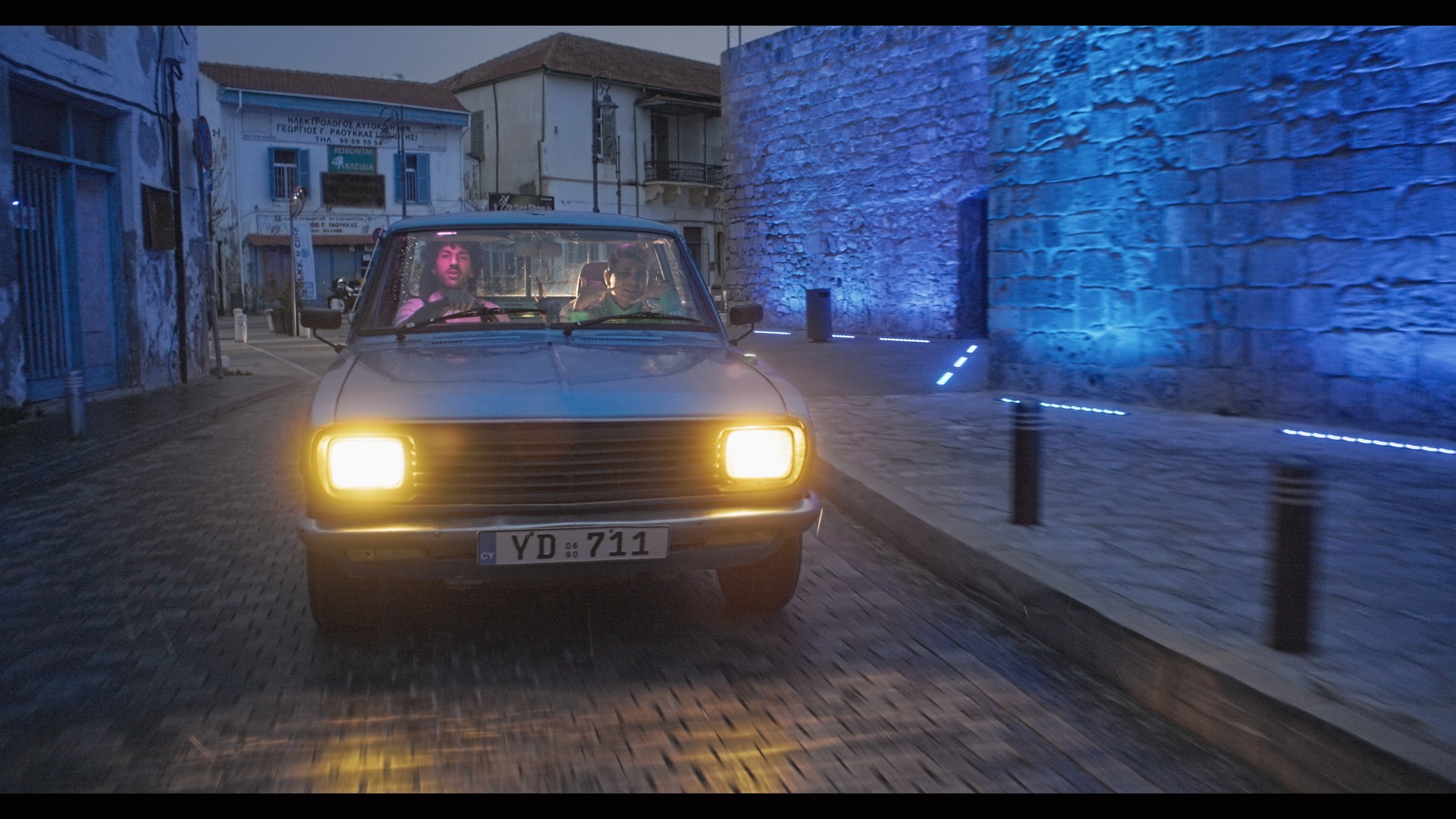 A singer raps Blue vintage car in the streets of Larnaca, at Cyprus for the filming of his music videoclip 