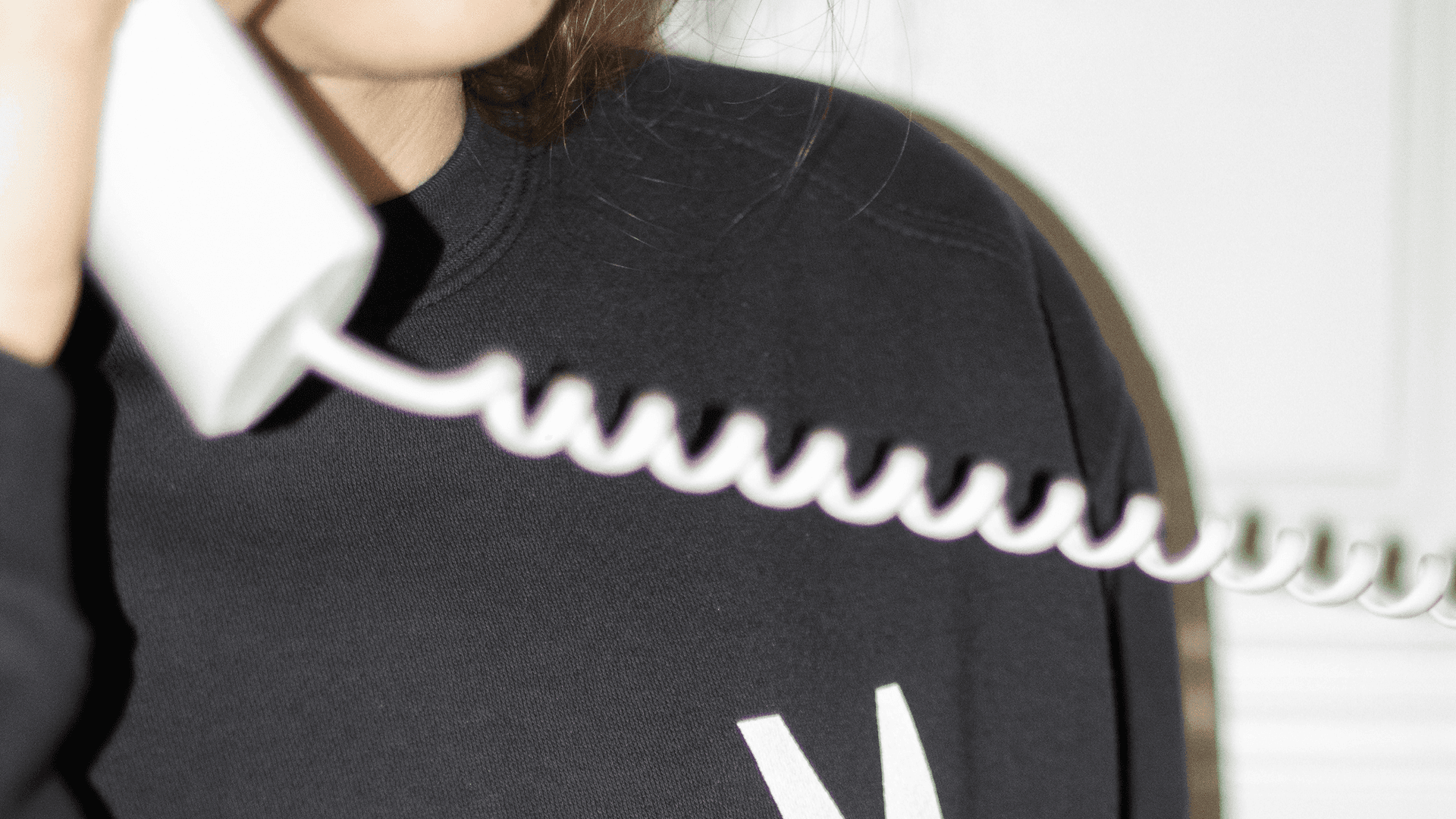 A close-up shot of a person in a black sweatshirt holding a white vintage-style telephone