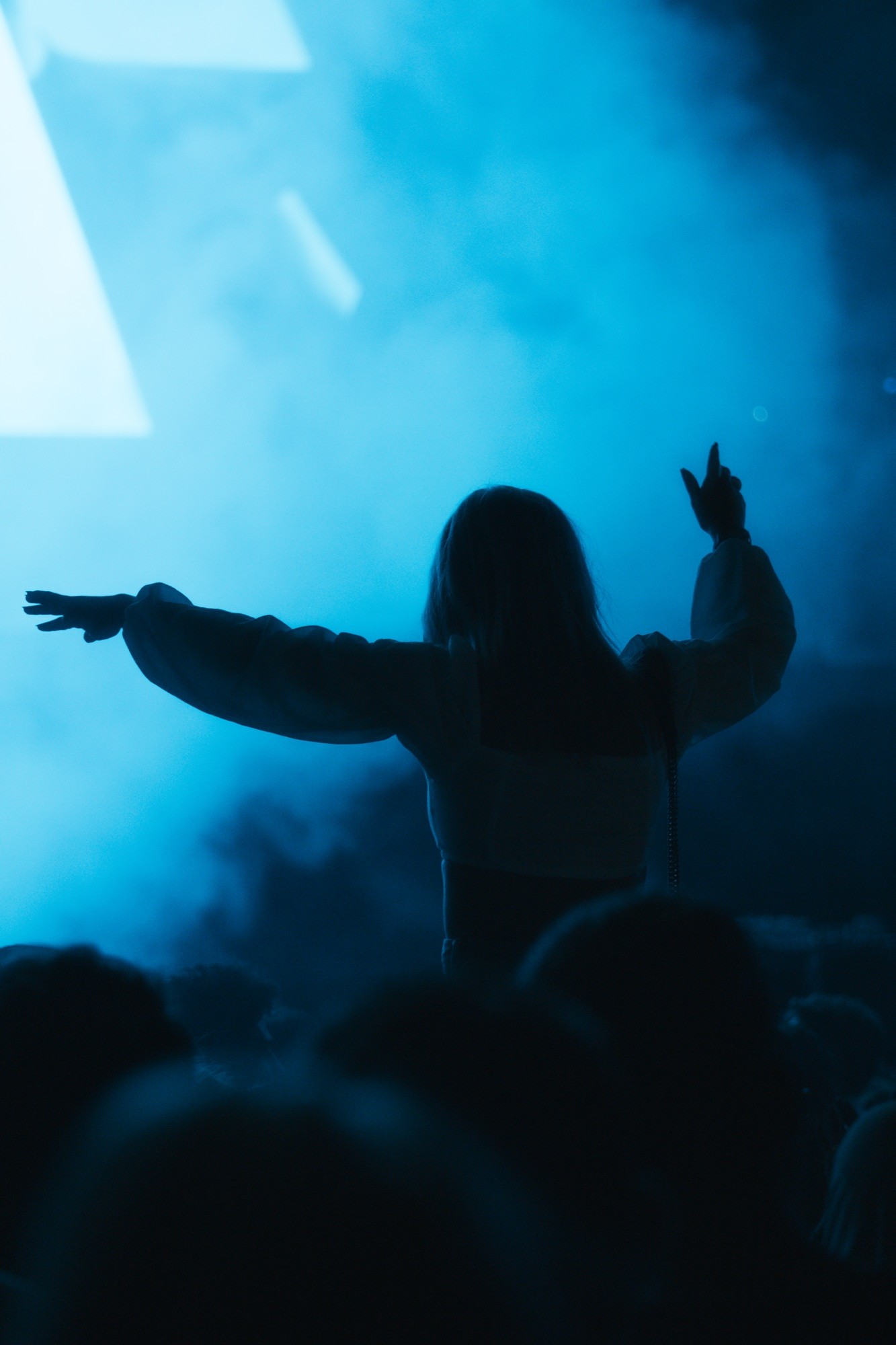 Silhouette im blauen Buehnenlicht mit ausgebreiteten Armen