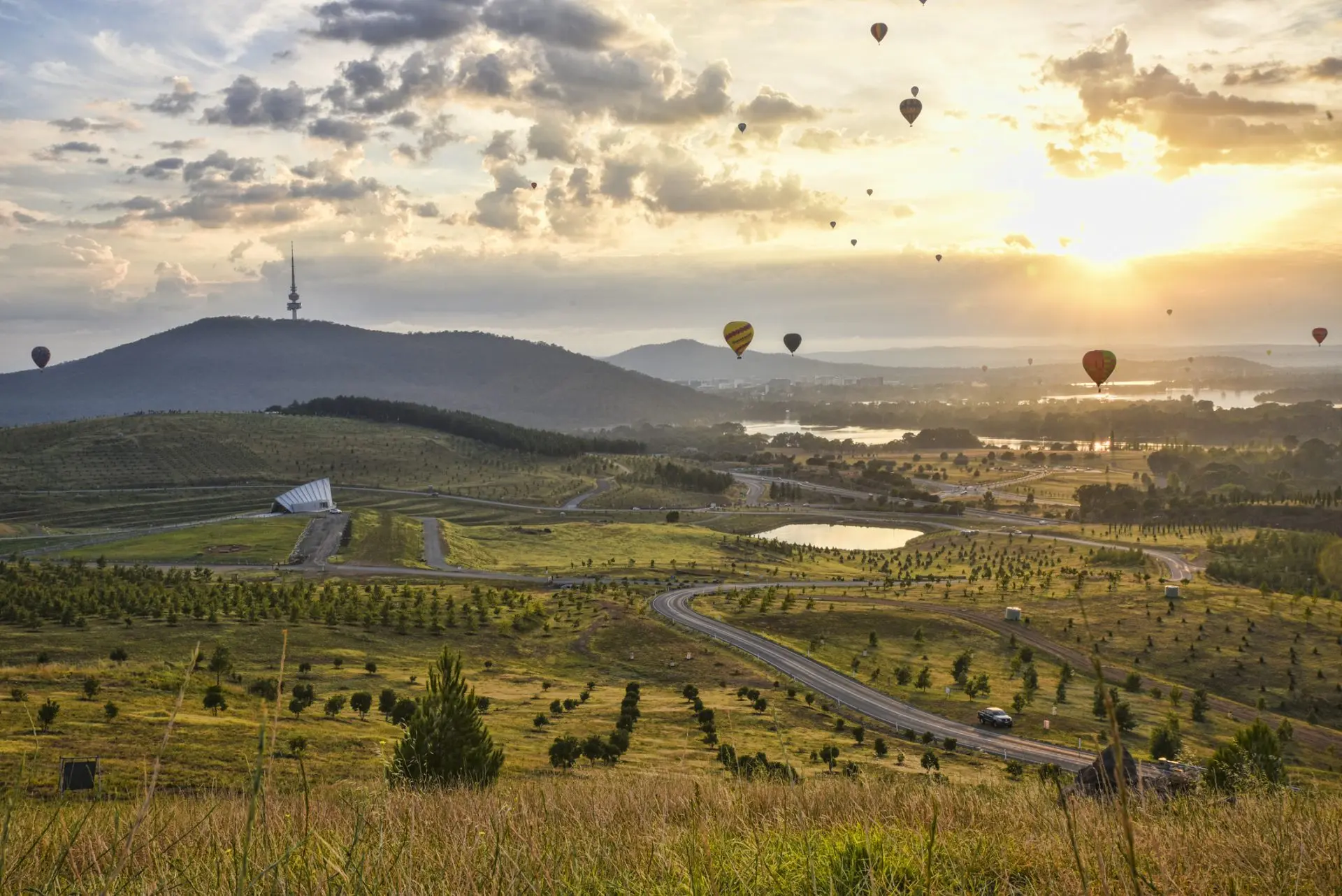 Hot air balloons over a hilly landscape at sunrise