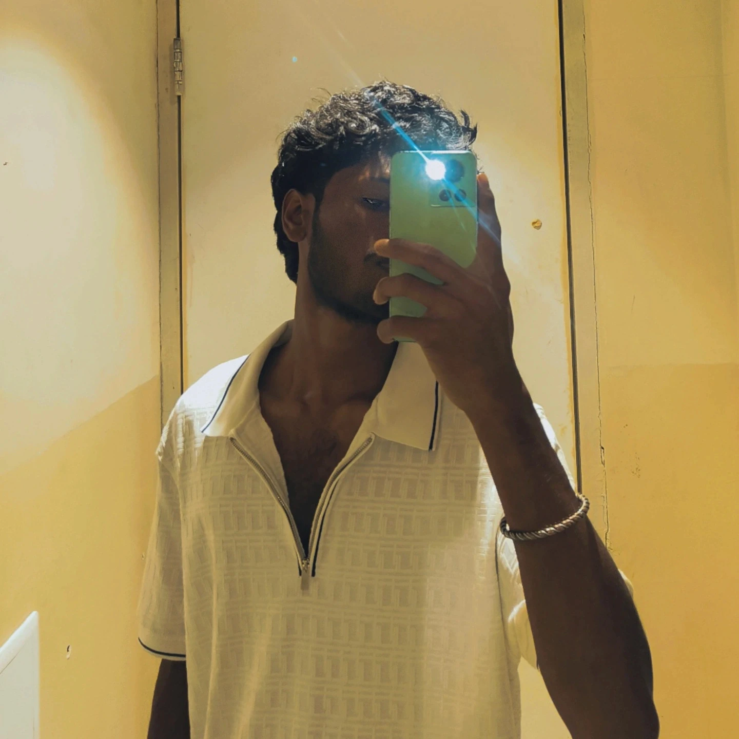 Young man with dark curly hair and beard, smiling.