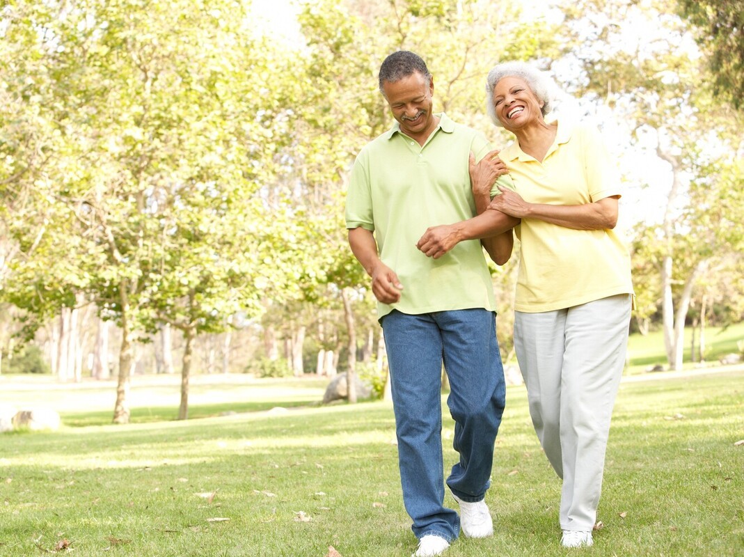 senior couple enjoying a good walking pace for weight loss outside in a park that works for their mobility issues