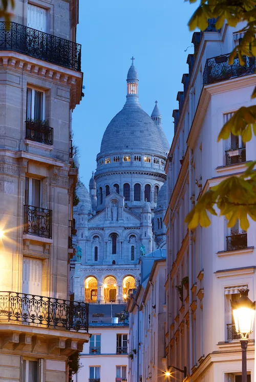 Basílica de Sacré-Cœur em Paris vista entre prédios históricos ao entardecer