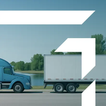 Blue semi-truck with a white trailer parked near a lake — representing GIA Group, LLC’s Motor Truck Cargo Insurance coverage for freight protection against loss, damage, or theft.