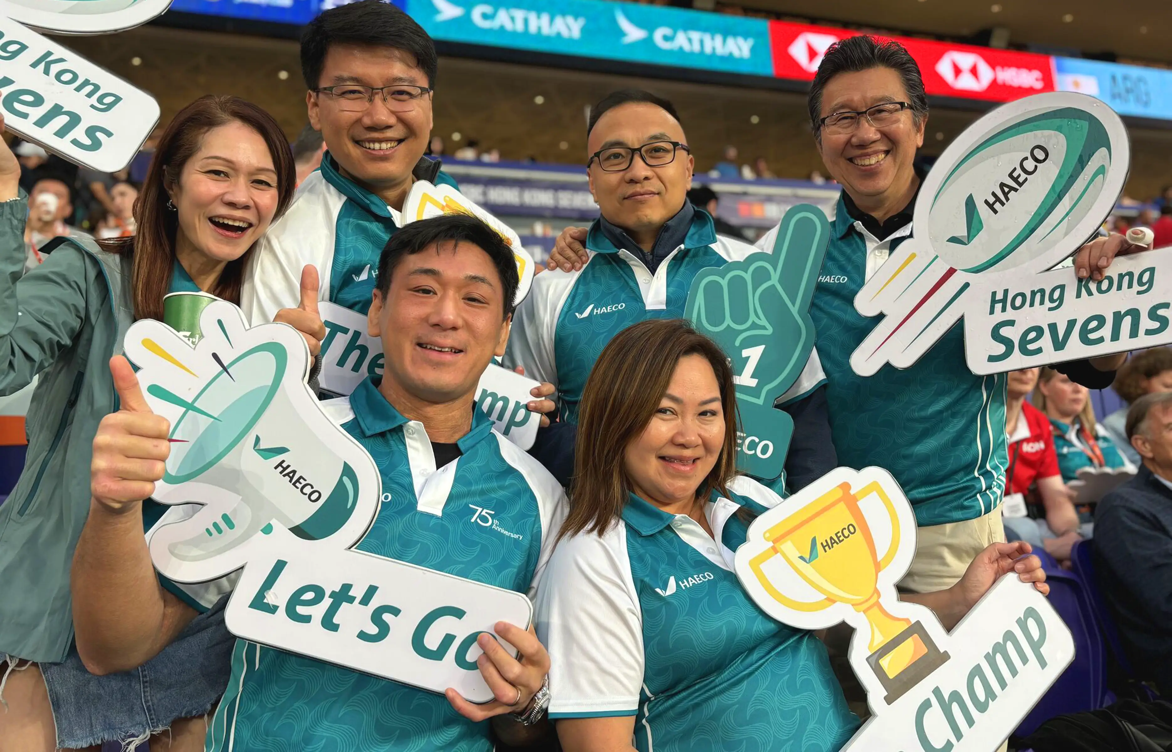 HAECO Rugby 7 event photography – team members celebrating with branded signage and aircraft motifs, showcasing global collaboration by Teatime Studio.