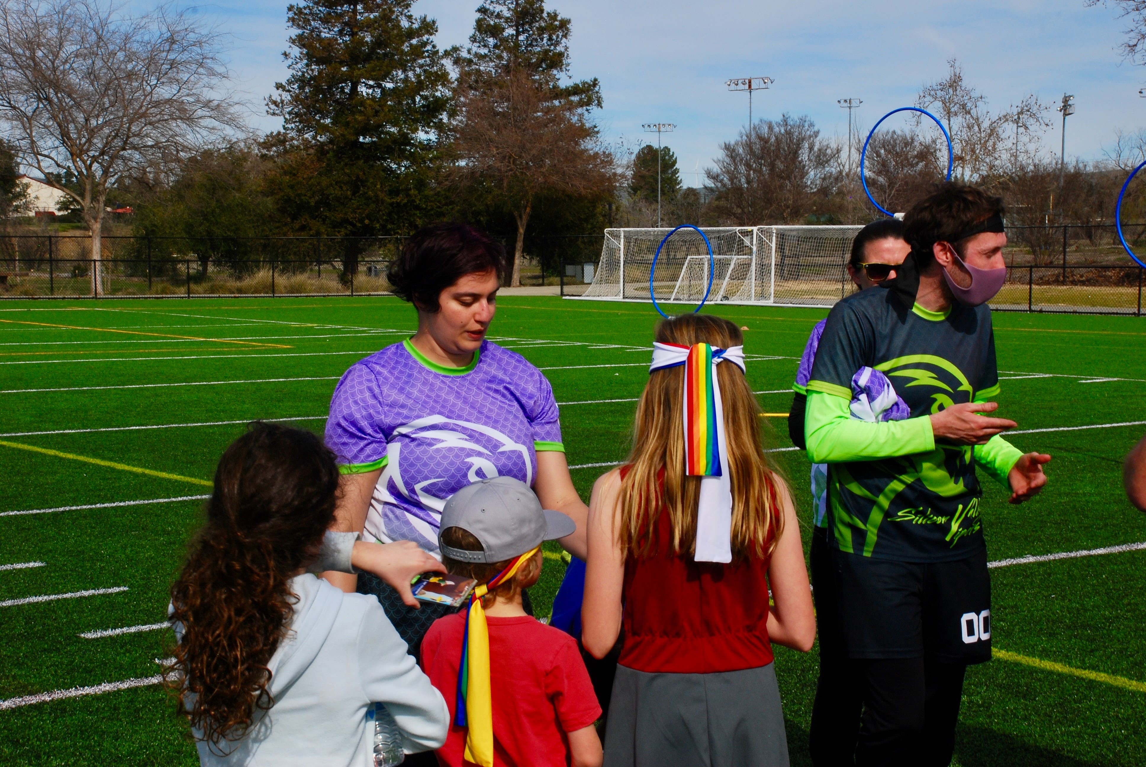 Silicon Valley Venom member hands an item out to children at a Kidditch event
