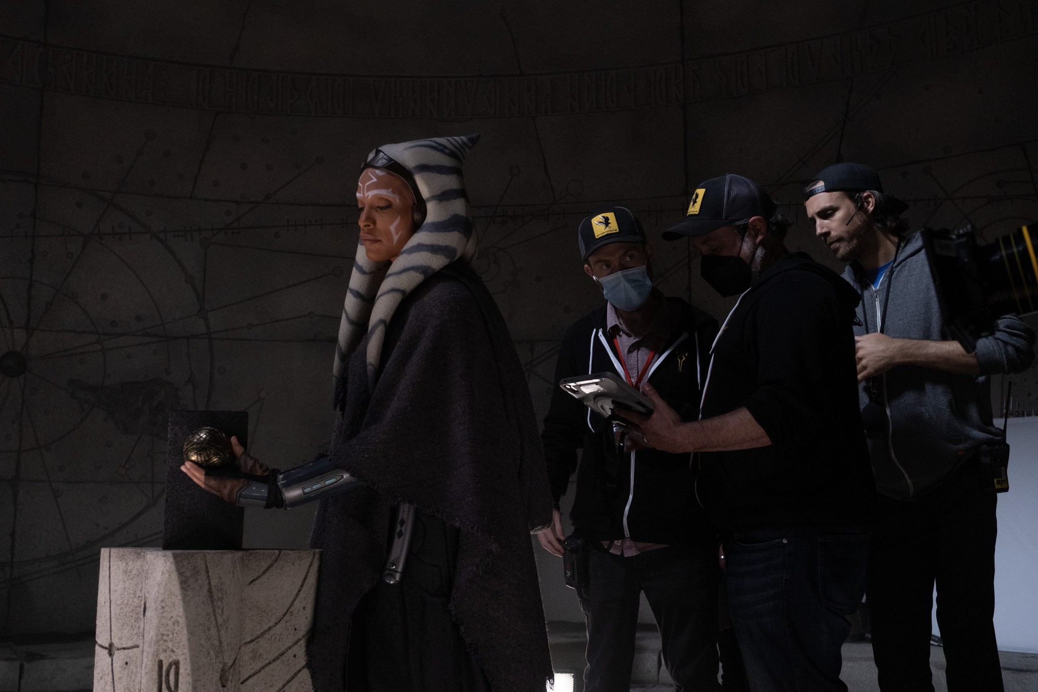 Rosario Dawson as Ahsoka holding a small object in fron of crew members