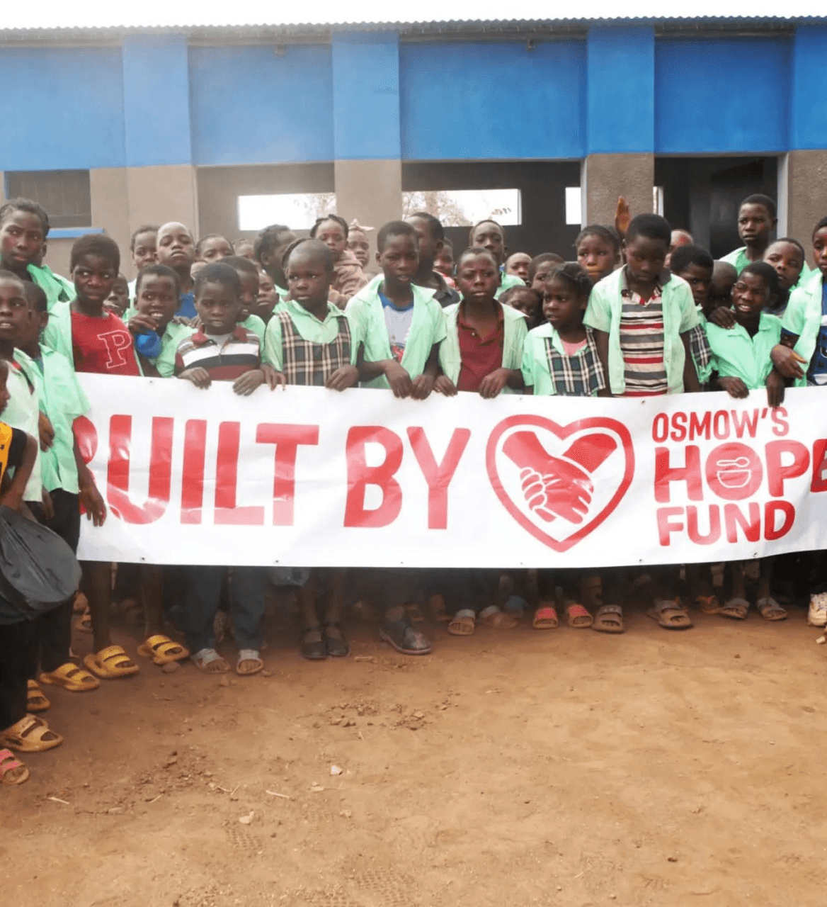 Community members holding Osmow's Hope Fund banner — built by Hope Fund sign