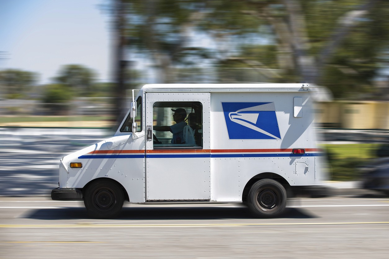 A USPS (United States Parcel Service) mail truck leaves for a delivery