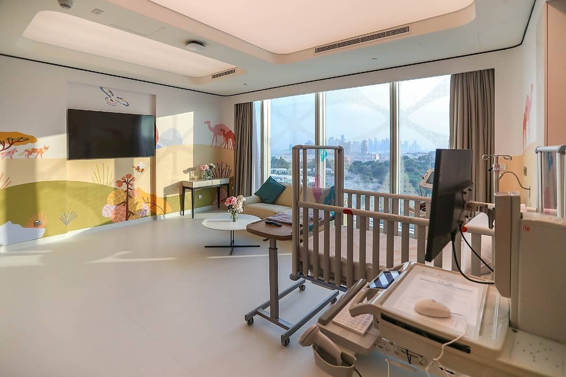 Une chambre de maternité lumineuse avec son berceau, au The View Hospital, à Doha, face aux tours de la ville