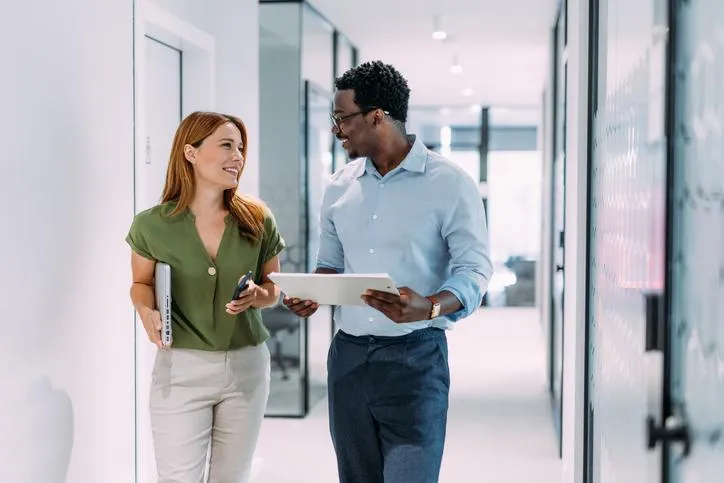 Business professionals discussing financial strategy in a modern office hallway.