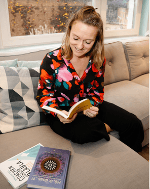 Audrey Vaesen houdt een boek vast op haar sofa in haar praktijk waar ze mensen coacht.