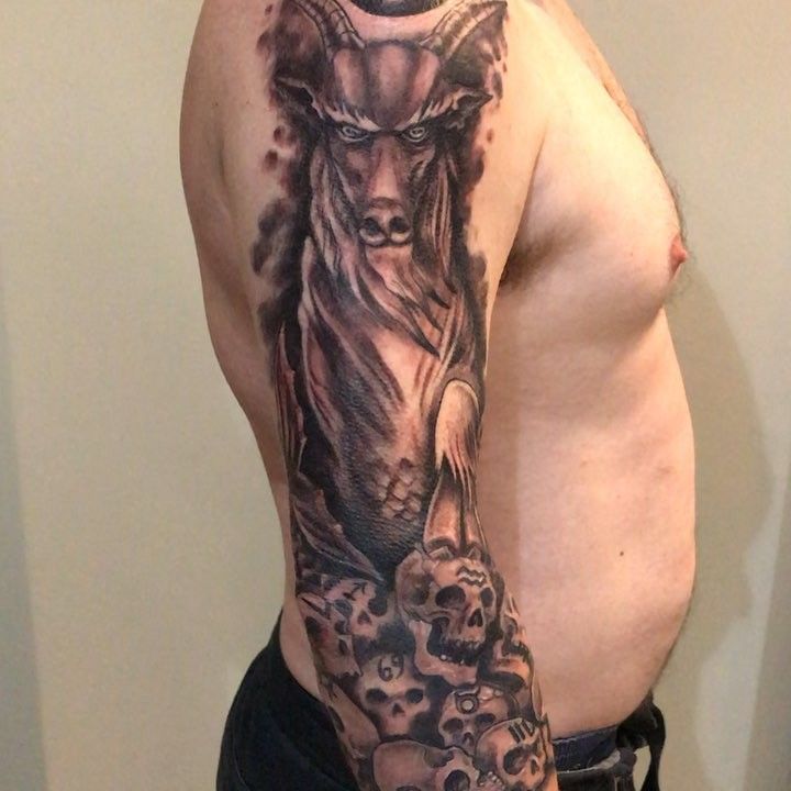 Black-and-grey warrior and skull sleeve tattoo on a forearm