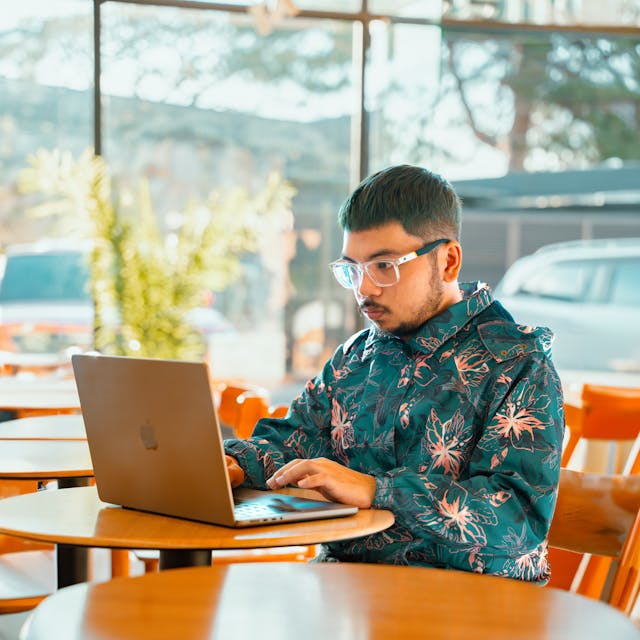 Closeup of woman wearing gold sweater typing on MacBook Pro