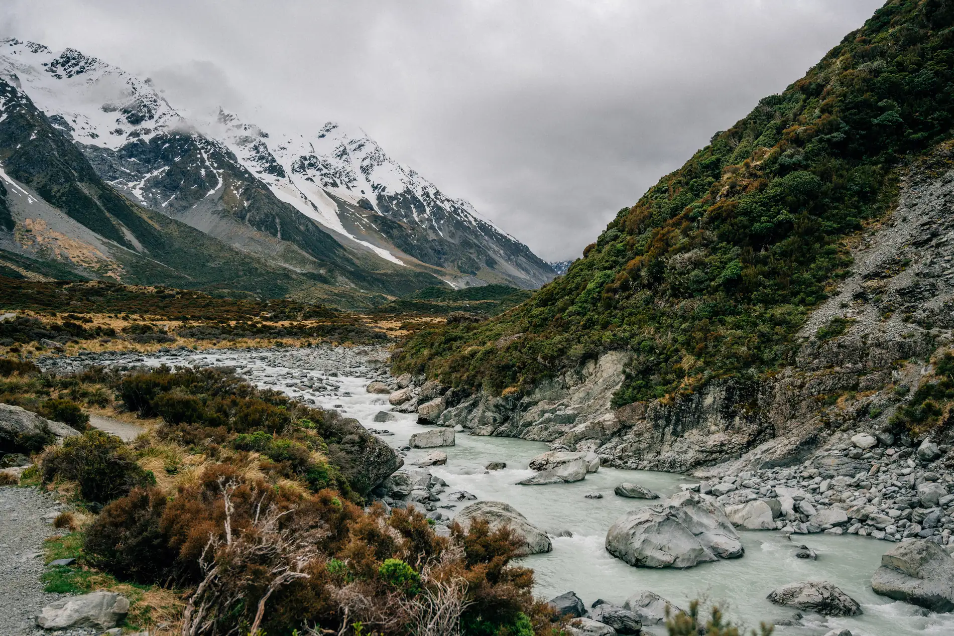 A wide glacial riverbed running out of a snow-capped mountain valley