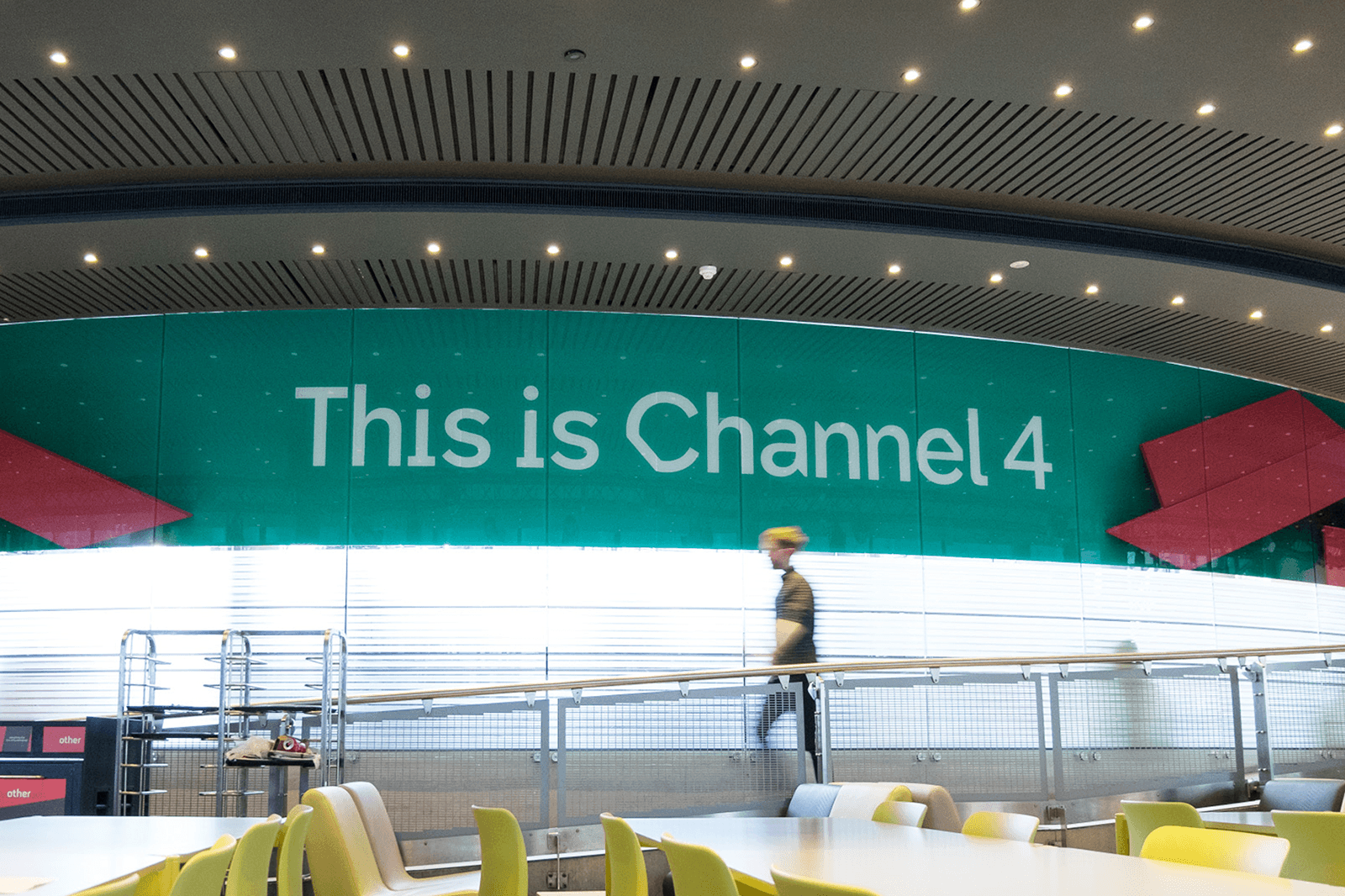 A large green wall displays the text "This is Channel 4," with a person walking in front of it.