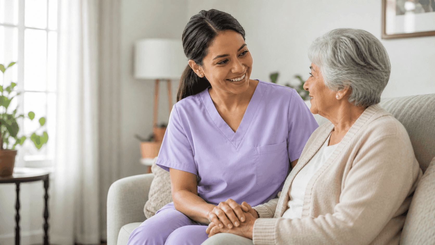 Caregiver and elderly woman sharing a relaxed conversation in a living room
