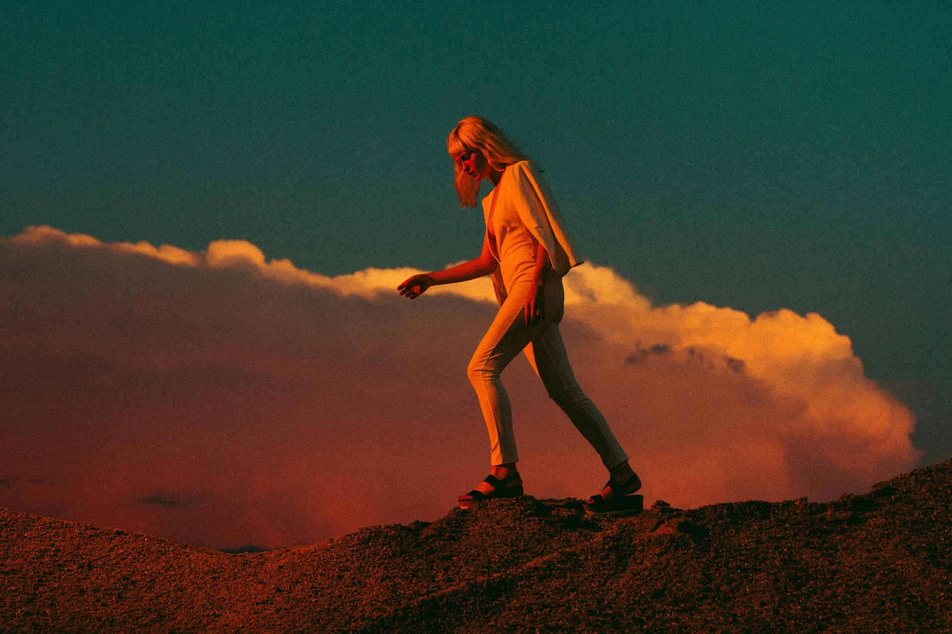 Person geht bedacht über eine erhöhte Landschaft vor weitem Himmel – visuelle Metapher für Orientierung, Klarheit und schrittweises Vorankommen.