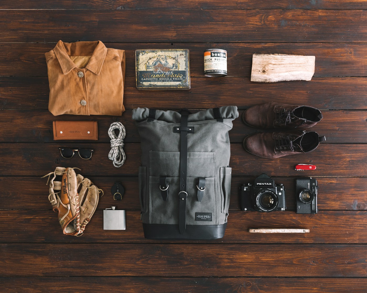 Travel clothes and a bag laid out on a wooden floor