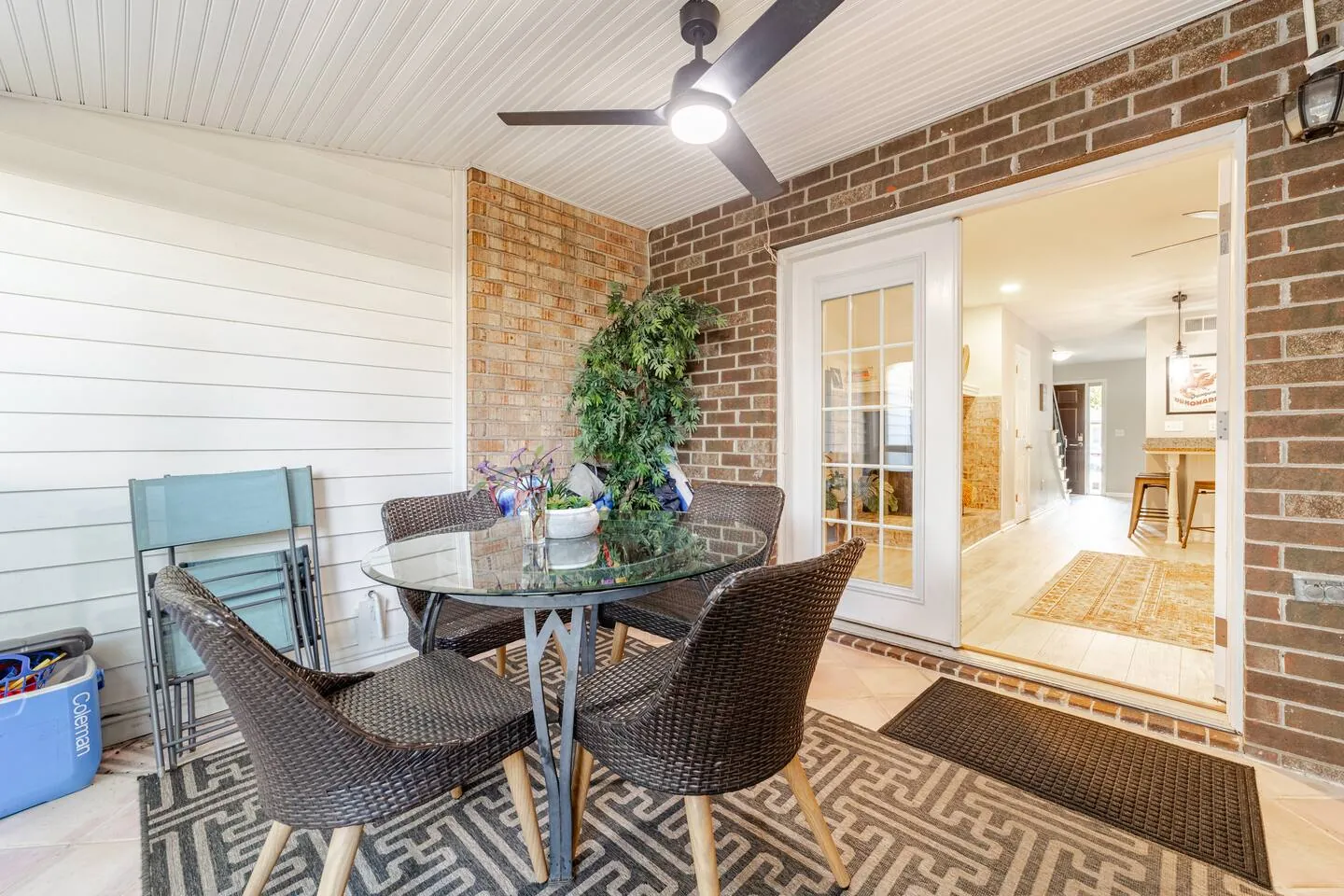 Screened porch with wicker dining chairs, opening to the living room