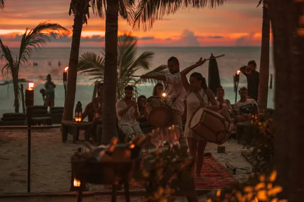 Sunset music event at Nômade Holbox, Holbox Mexico, with drums, torches, palm trees and guests