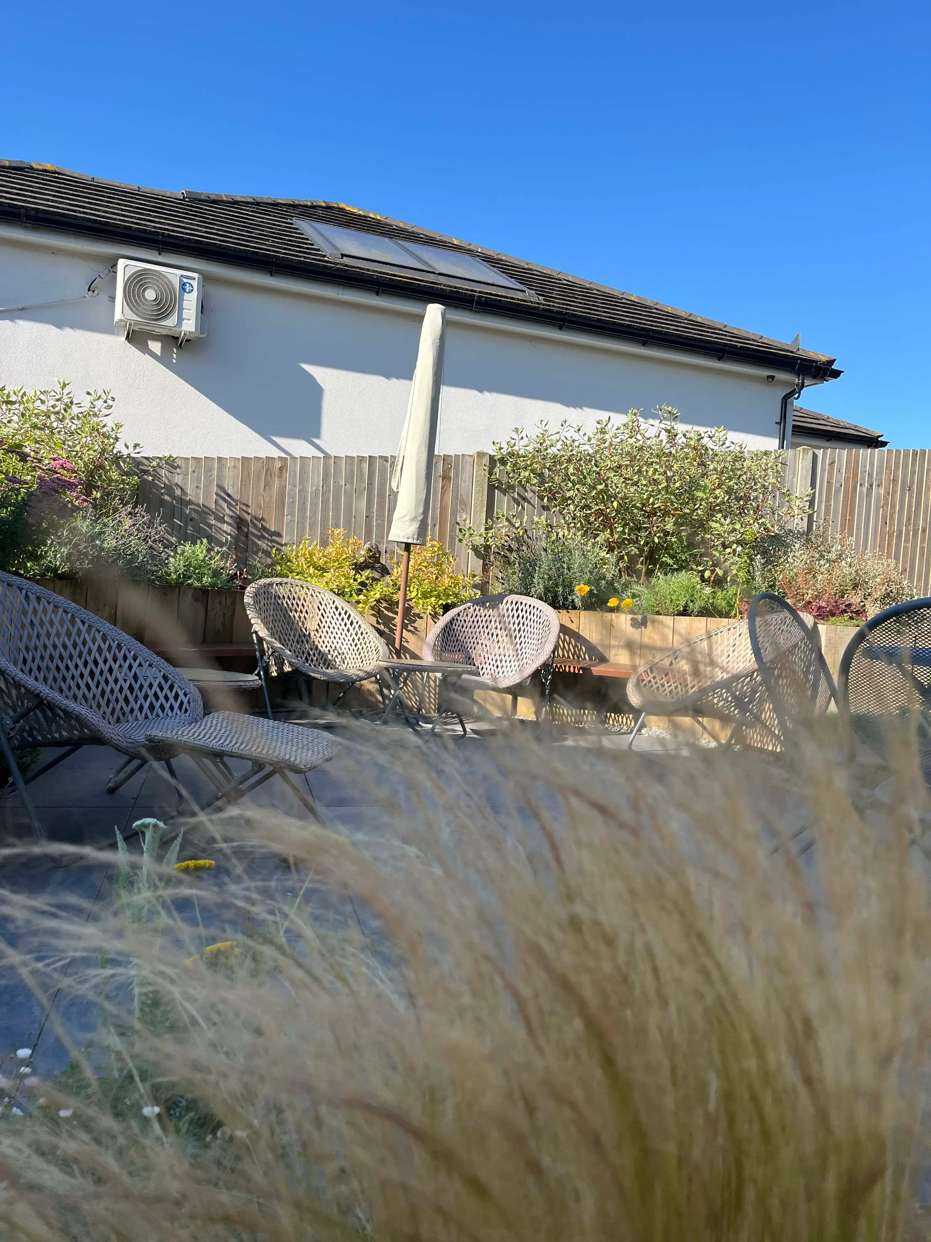 A serene outdoor scene featuring a house, landscaping, rocks, and clear blue sky.