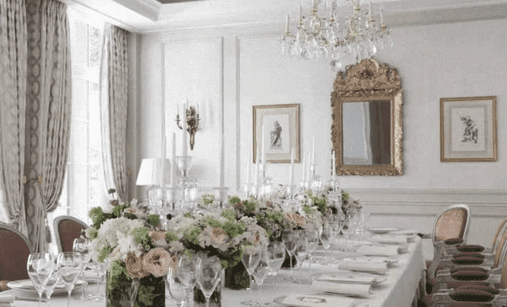 An opulent dining room adorned with floral arrangements, crystal chandeliers, and ornate mirrors — evoking timeless Parisian elegance and celebration.  