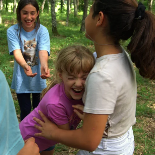 Bambini che giocano e si abbracciano durante un campo estivo in natura, sviluppando relazione, fiducia in sé e crescita personale