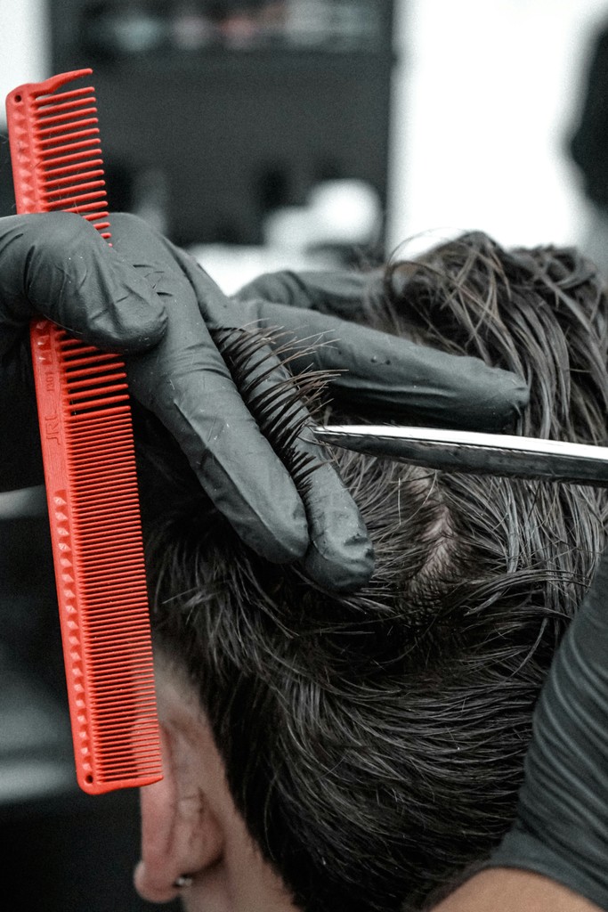 A man getting a haircut with a red comb