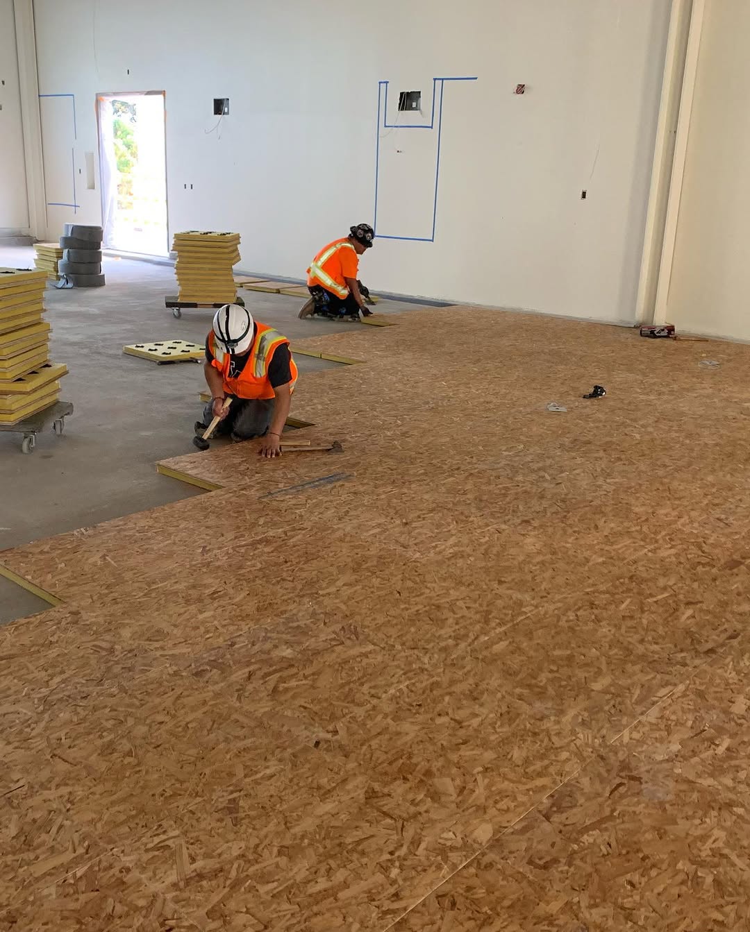 Plywood underlayment being laid over a prepared slab