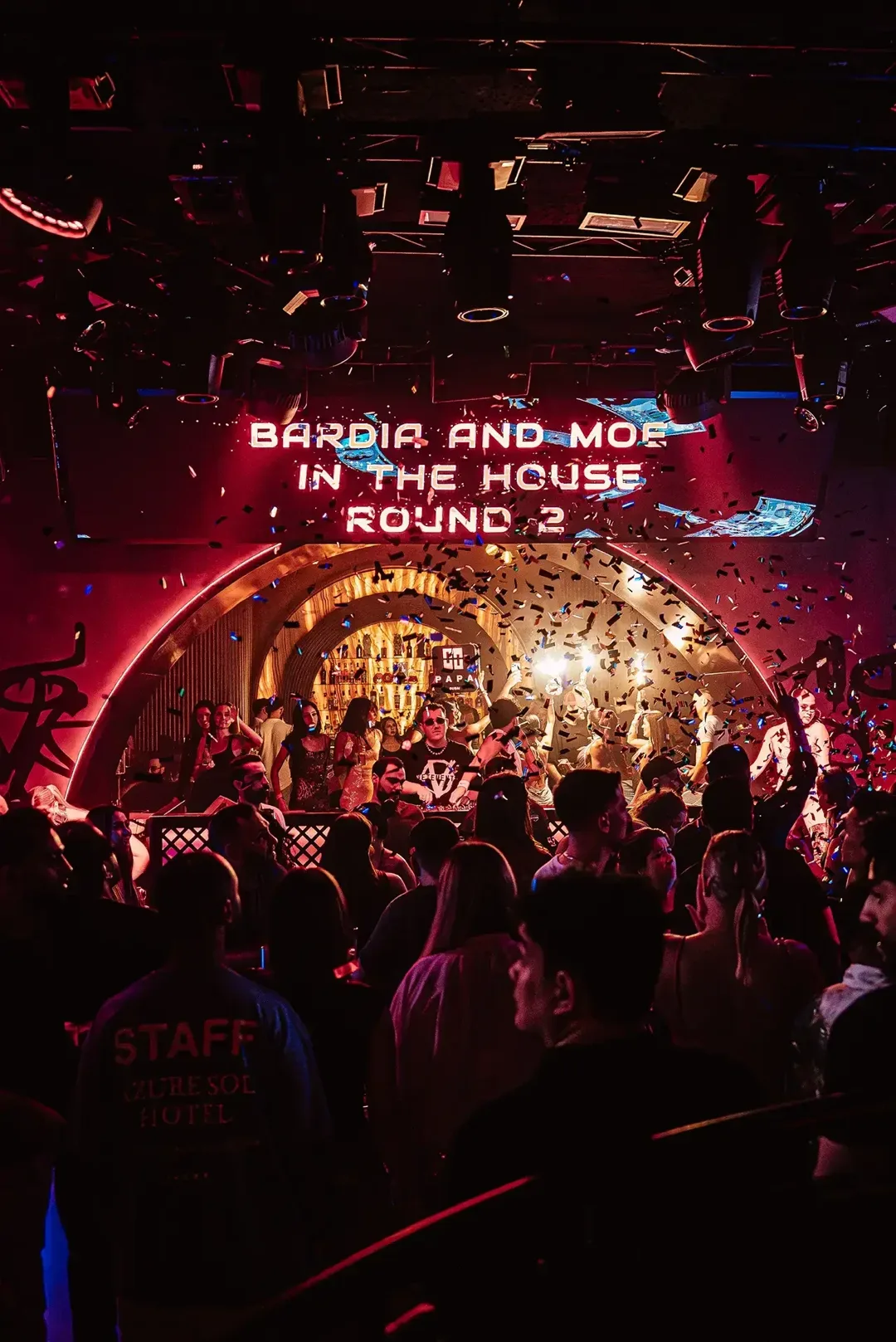 DJ booth under a glowing arch at PAPA Dubai, with confetti raining over a packed dance floor