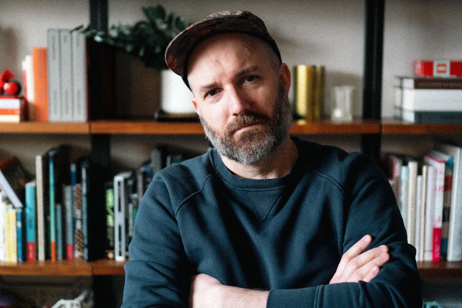 Image of Chuck in front of a bookshelf, looking much more serious than usual.