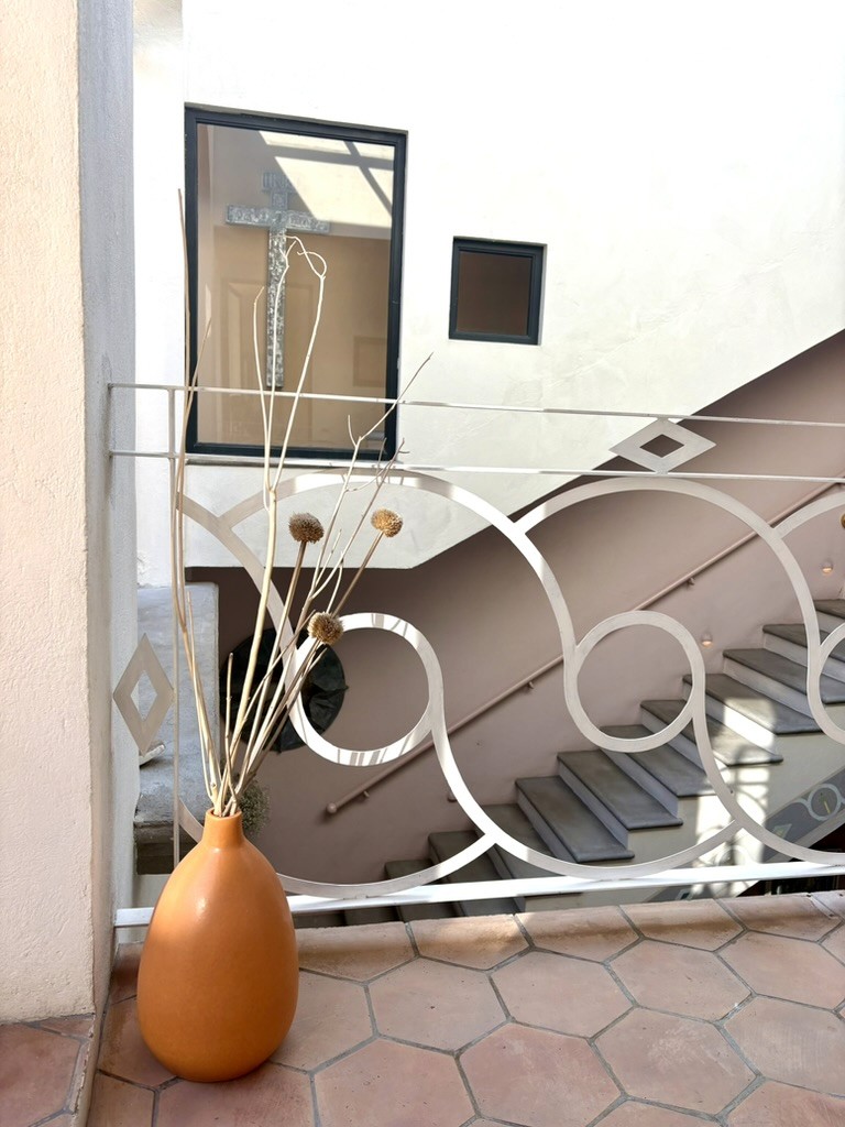 Orange vase, white railing, and pink staircase at Casa de los Tíos